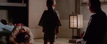 Movie still from “Lone Wolf and Cub: Baby Cart to Hades” (1972), directed by Kenji Misumi – A little boy standing in front of a lamp in a room; Wide shot, Low angle