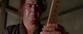 Movie still from “Lone Wolf and Cub: Baby Cart to Hades” (1972), directed by Kenji Misumi – A man holding a piece of wood in front of his face; Close Up shot, Low angle