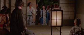 Movie still from “Lone Wolf and Cub: Baby Cart to Hades” (1972), directed by Kenji Misumi – An image of a group of people standing in front of a building; Wide shot, Over the shoulder angle