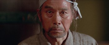 Movie still from “Lone Wolf and Cub: Baby Cart to Hades” (1972), directed by Kenji Misumi – An older man with a bandaged head stares into the camera; Close Up shot, Low angle