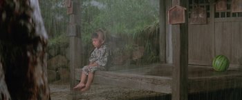 Movie still from “Lone Wolf and Cub: Baby Cart to Hades” (1972), directed by Kenji Misumi – A little boy sitting on a porch in the rain; Wide shot, High angle