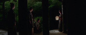 Movie still from “Lone Wolf and Cub: Baby Cart to Hades” (1972), directed by Kenji Misumi – A group of people standing in the dark near a tree; Wide shot, High angle