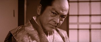 Movie still from “Lone Wolf and Cub: Baby Cart to Hades” (1972), directed by Kenji Misumi – An old photo of a man in a suit and tie looking angry; Close Up shot, Low angle
