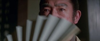 Movie still from “Lone Wolf and Cub: Baby Cart to Hades” (1972), directed by Kenji Misumi – A person holding a fan; Extreme Close Up shot, Over the shoulder angle