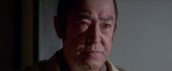 Movie still from “Lone Wolf and Cub: Baby Cart to Hades” (1972), directed by Kenji Misumi – An older asian man with a goatee looking at the camera; Close Up shot, Low angle