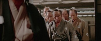 Movie still from “Lone Wolf and Cub: Baby Cart to Hades” (1972), directed by Kenji Misumi – A group of men standing next to each other in a room; Close Up shot, Over the shoulder angle