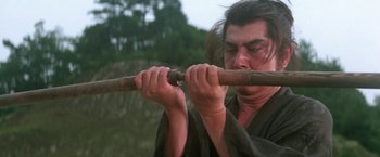 Movie still from “Lone Wolf and Cub: Baby Cart to Hades” (1972), directed by Kenji Misumi – A man holding a wooden stick in his hands; Close Up shot, Low angle