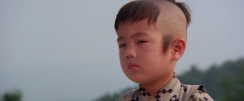 Movie still from “Lone Wolf and Cub: Baby Cart to Hades” (1972), directed by Kenji Misumi – A young boy with a shaved head looks at the camera; Close Up shot, High angle