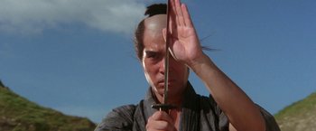 Movie still from “Lone Wolf and Cub: Baby Cart to Hades” (1972), directed by Kenji Misumi – A man holding a sword up to his face; Close Up shot, Low angle
