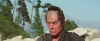 Movie still from “Lone Wolf and Cub: Baby Cart to Hades” (1972), directed by Kenji Misumi – A man with a shaved head is wearing a kimono; Close Up shot, High angle