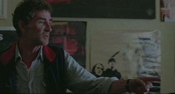 Movie still from “Looking for Eric” (2009), directed by Ken Loach – A man sitting at a table in front of a painting; Medium shot, Over the shoulder angle