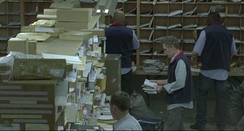 Movie still from “Looking for Eric” (2009), directed by Ken Loach – A group of men working in a room filled with boxes; Wide shot, High angle
