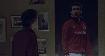 Movie still from “Looking for Eric” (2009), directed by Ken Loach – A man standing in front of a mirror in a room; Medium shot, Over the shoulder angle