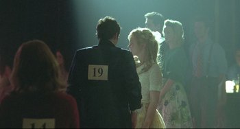 Movie still from “Looking for Eric” (2009), directed by Ken Loach – A man and a woman are standing in front of other people; Medium shot, Over the shoulder angle