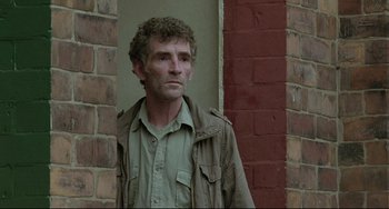 Movie still from “Looking for Eric” (2009), directed by Ken Loach – A man standing in front of a brick wall; Medium shot, Low angle