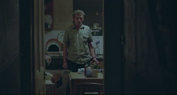 Movie still from “Looking for Eric” (2009), directed by Ken Loach – A man standing at a table in a kitchen; Medium shot, Over the shoulder angle