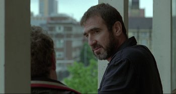 Movie still from “Looking for Eric” (2009), directed by Ken Loach – A man with a goatee is looking out of a window; Close Up shot, Over the shoulder angle