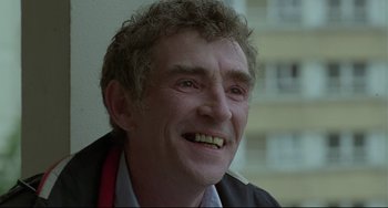 Movie still from “Looking for Eric” (2009), directed by Ken Loach – An older man smiling for the camera; Close Up shot, Low angle