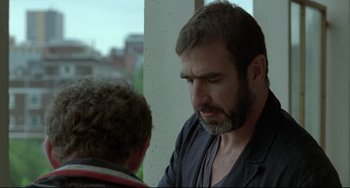 Movie still from “Looking for Eric” (2009), directed by Ken Loach – A man with a gray beard talking to another man; Close Up shot, Over the shoulder angle