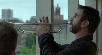 Movie still from “Looking for Eric” (2009), directed by Ken Loach – A man holding a trumpet in his hands; Close Up shot, Low angle
