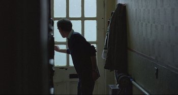 Movie still from “Looking for Eric” (2009), directed by Ken Loach – A man standing in front of an open door; Medium shot, Over the shoulder angle
