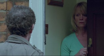 Movie still from “Looking for Eric” (2009), directed by Ken Loach – A woman standing in front of a man in front of a door; Medium shot, Over the shoulder angle