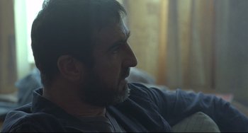Movie still from “Looking for Eric” (2009), directed by Ken Loach – A person sitting on a couch; Close Up shot, Over the shoulder angle