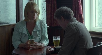 Movie still from “Looking for Eric” (2009), directed by Ken Loach – Two people sitting at a table with a glass of beer in front of them; Medium shot, Over the shoulder angle