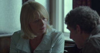 Movie still from “Looking for Eric” (2009), directed by Ken Loach – A woman sitting in front of a man in front of a window; Close Up shot, Over the shoulder angle