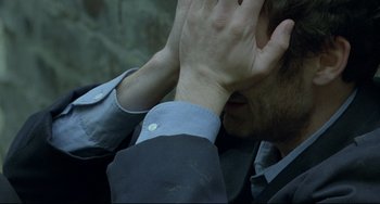 Movie still from “Looking for Eric” (2009), directed by Ken Loach – A man with his hands covering his face; Close Up shot, High angle