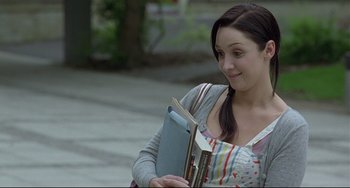 Movie still from “Looking for Eric” (2009), directed by Ken Loach – A woman is holding a book while standing on the sidewalk; Close Up shot, Over the shoulder angle