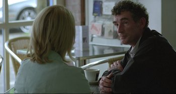 Movie still from “Looking for Eric” (2009), directed by Ken Loach – A man and a woman are sitting at a table; Medium shot, Over the shoulder angle