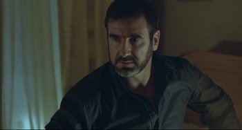 Movie still from “Looking for Eric” (2009), directed by Ken Loach – A person sitting in a room; Close Up shot, Over the shoulder angle