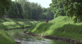 Movie still from “Looking for Eric” (2009), directed by Ken Loach – A couple of people walking down the side of a river; Extreme Wide shot, High angle