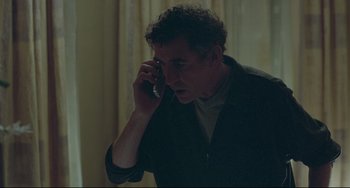 Movie still from “Looking for Eric” (2009), directed by Ken Loach – A man talking on a cell phone while standing in a room; Medium shot, High angle