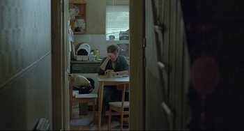 Movie still from “Looking for Eric” (2009), directed by Ken Loach – A man sitting at a table with a cup of coffee; Medium shot, Over the shoulder angle
