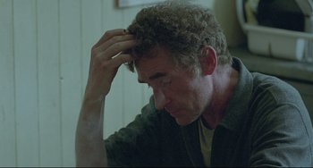 Movie still from “Looking for Eric” (2009), directed by Ken Loach – A person with his hand on his head; Close Up shot, Over the shoulder angle