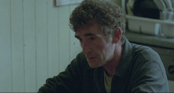 Movie still from “Looking for Eric” (2009), directed by Ken Loach – A person sitting at a table; Close Up shot, Over the shoulder angle