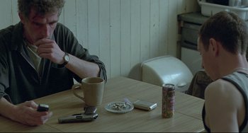 Movie still from “Looking for Eric” (2009), directed by Ken Loach – A man sitting at a table with a cup of coffee; Medium shot, High angle