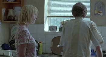 Movie still from “Looking for Eric” (2009), directed by Ken Loach – A woman and a man in a kitchen looking in a mirror; Medium shot, Over the shoulder angle