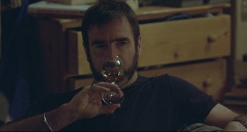 Movie still from “Looking for Eric” (2009), directed by Ken Loach – A man holding a wine glass in his right hand; Close Up shot, Over the shoulder angle