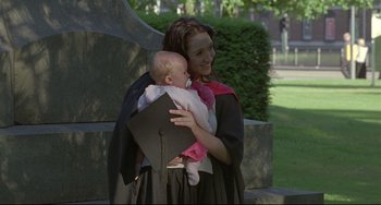 Movie still from “Looking for Eric” (2009), directed by Ken Loach – A woman holding a baby in her arms and wearing a graduation cap; Medium shot, Over the shoulder angle