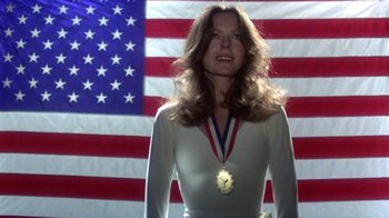 A woman standing in front of an american flag with a medal around her neck