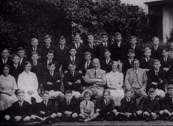 Movie still from “Lord of the Flies” (1963), directed by Peter Brook – An old photo of a group of people sitting on the ground; Wide shot, High angle