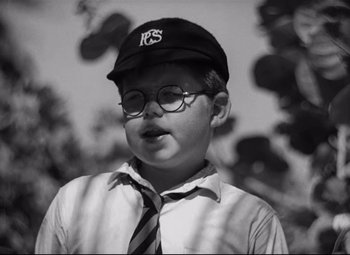 Movie still from “Lord of the Flies” (1963), directed by Peter Brook – A young boy wearing glasses and a hat; Close Up shot, Low angle