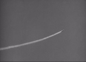 Movie still from “Lord of the Flies” (1963), directed by Peter Brook – An airplane is flying in the sky with a trail of smoke coming out of it; Extreme Wide shot, Low angle