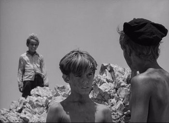 Movie still from “Lord of the Flies” (1963), directed by Peter Brook – A group of young people standing on top of a mountain; Medium shot, Over the shoulder angle
