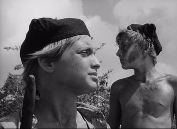 Movie still from “Lord of the Flies” (1963), directed by Peter Brook – Two young men are standing in the grass; Close Up shot, Low angle