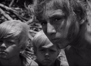 Movie still from “Lord of the Flies” (1963), directed by Peter Brook – A black - and - white photo of a man and two young boys; Close Up shot, Low angle