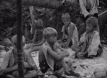 Movie still from “Lord of the Flies” (1963), directed by Peter Brook – A black and white photo of a group of children sitting on the ground; Medium shot, High angle